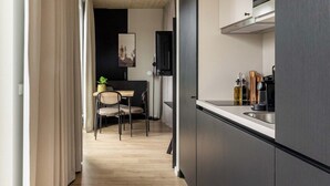 Een moderne keuken met donkere kastjes, een ingebouwde kookplaat en een eethoek met een tafel en stoelen.