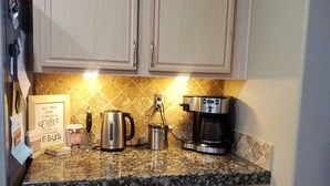 A kitchen with light wood cabinets, a granite countertop, a coffee maker, a kettle, and a framed sign. - Beautiful Townhouse close to Lake Tahoe (Reno)