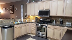 A modern kitchen with stainless steel appliances, light wood cabinets, and a granite countertop. - Beautiful Townhouse close to Lake Tahoe (Reno)