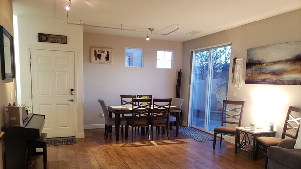 A spacious living room with a dining area, hardwood floors, a piano, and a large window with a view. - Beautiful Townhouse close to Lake Tahoe (Reno)