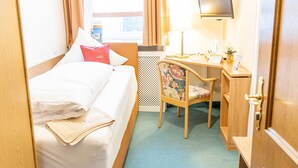 Ein Hotelzimmer mit Bett, Schreibtisch, Stuhl, Fernseher und einem fensterbepflanzten Fenster.