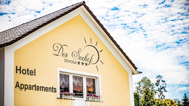 Ein gelbes Gebäude mit einem Schild, auf dem „Der Seefhof DEHOGA“ und „Hotel Apartments“ steht.