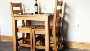 A wooden dining table with two chairs, a wine bottle, and two wine glasses.