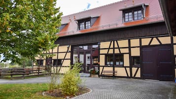A building with a traditional half-timbered facade, a paved courtyard, and a wooden fence.