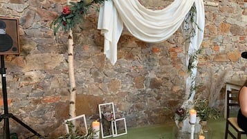 A stone wall, a white draped cloth, a speaker, and framed pictures.