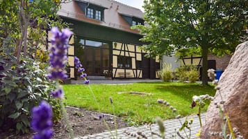 A building with a traditional half-timbered facade, a paved courtyard, and surrounding greenery.