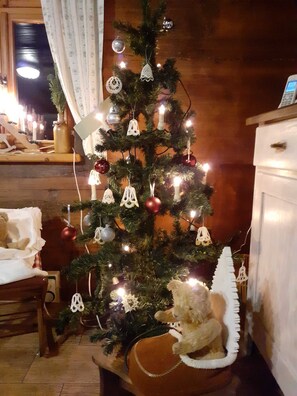 Un árbol de Navidad con luces y adornos, un oso de peluche y un jarrón sobre una mesa.