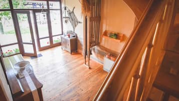Ein rustikales Interieur mit einer Bank, einem kleinen Tisch, einer hängenden Leuchte und Wanddekoration.