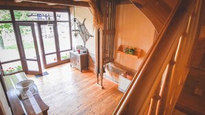 A wooden interior with a bench, a small table, a hanging light fixture, and a rustic wall decoration.