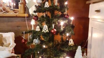 A Christmas tree with lights and ornaments, a teddy bear, and a vase on a table.
