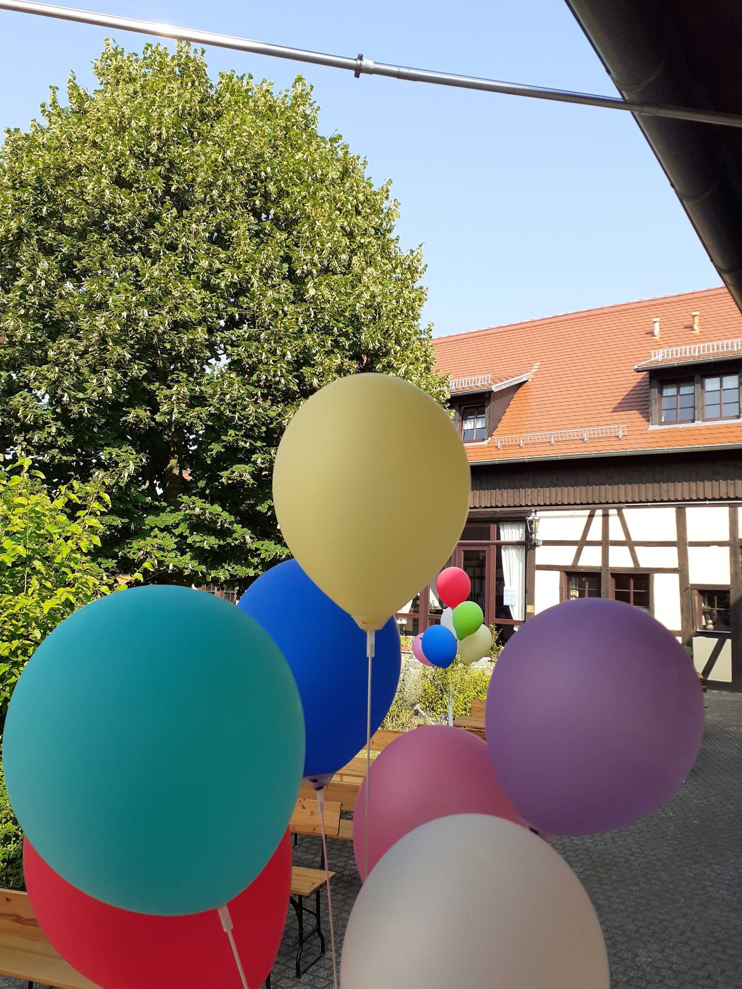 Ein Gebäude mit rotem Ziegeldach und einem großen Baum im Hintergrund.
