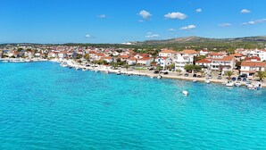 A coastal town with a marina, houses with red roofs, and a clear blue sea. - Apartments Jelena (Rogoznica)