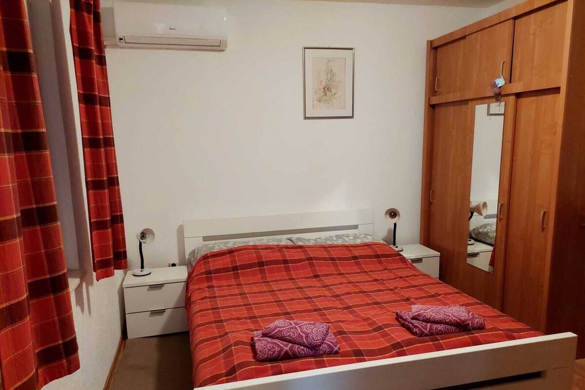 A bedroom with a bed, a nightstand, a mirror, and a wardrobe.