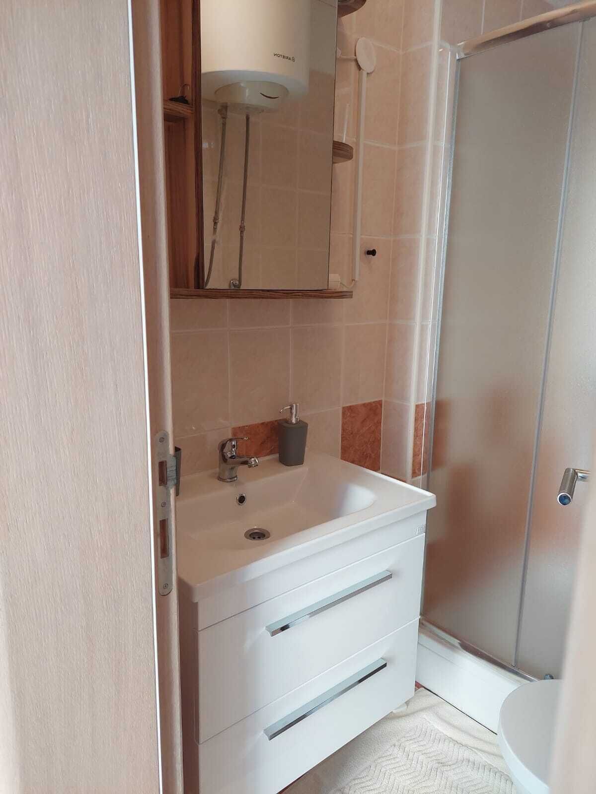A bathroom with a white sink, a mirror, and a shower.