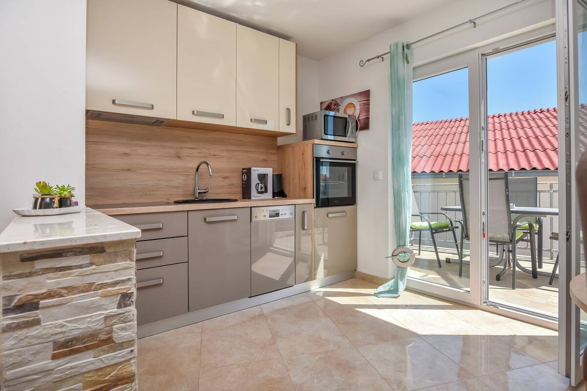 A modern kitchen with a stone accent wall, a built-in oven, and a microwave on the countertop.