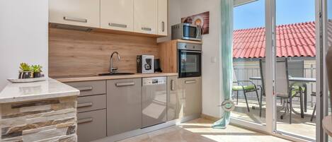 A modern kitchen with a stone accent wall, a built-in oven, and a microwave on the countertop.