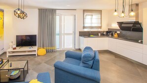 A modern living room with a blue sofa, a flat-screen TV, and a glass coffee table. - House Villa Verdi (Tkon)