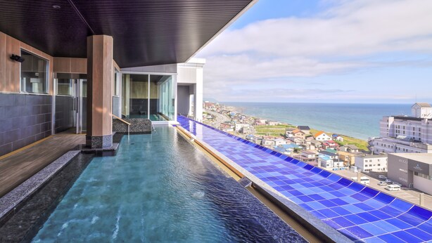 Une piscine à débordement moderne offrant une vue dégagée sur la mer et, en arrière-plan, sur le paysage urbain.