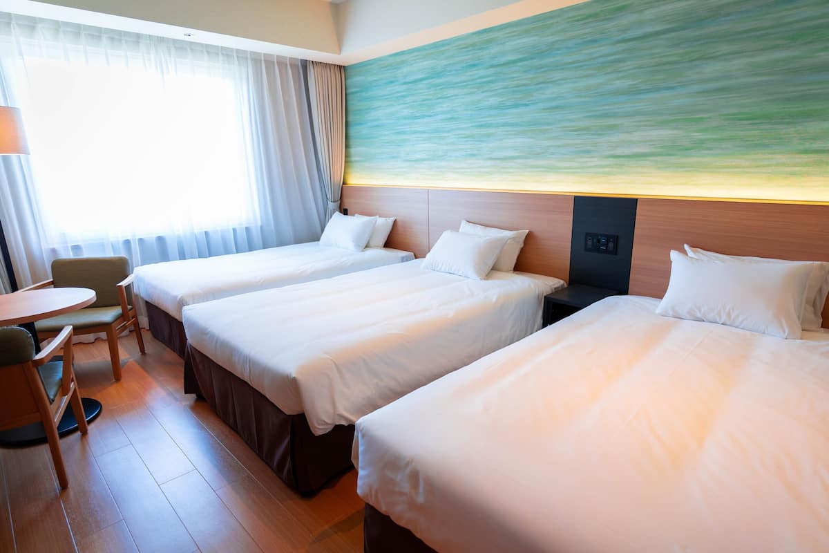 A hotel room with two beds, a desk, and a chair.