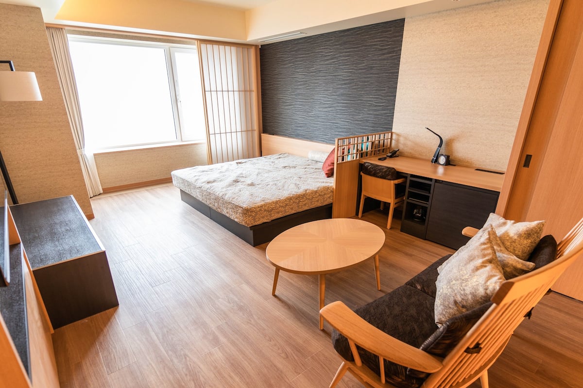 A compact living space with a bed, a small round table, a sofa, and a desk area.