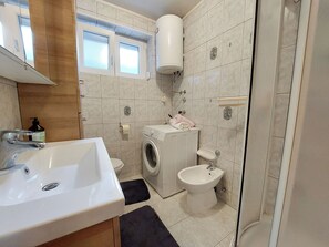A compact bathroom with a sink, toilet, washing machine, and bidet. - Apartment Klara (Dramalj)