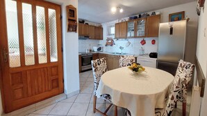 A kitchen with wooden cabinets, a stainless steel refrigerator, a microwave, and a dining table with a floral tablecloth. - Apartment Klara (Dramalj)