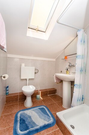 A bathroom with a skylight, toilet, sink, and bathtub. - Apartments Mirjana Blue Beach (Vodice)