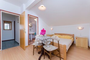 A bedroom with a bed, a bedside table, a nightstand, a chair, a table with a lace tablecloth, and a vase with flowers. - Apartments Mirjana Blue Beach (Vodice)