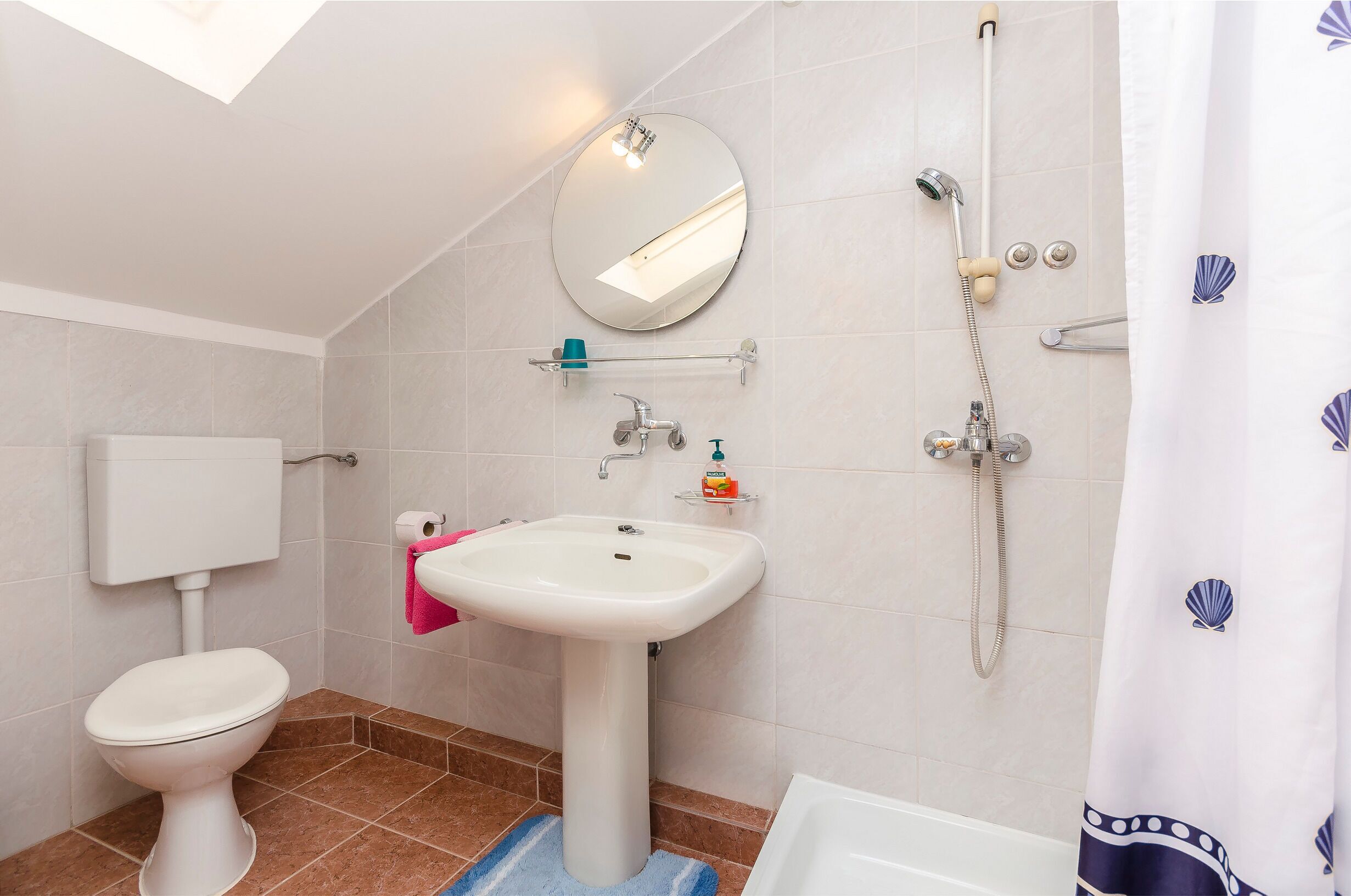 A bathroom with a toilet, sink, and shower.
