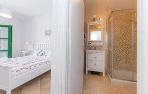 A bedroom with a bed, bedside table, and a green-framed window. - Villa Ibis (Vrana)