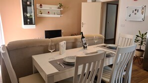 Ein Essbereich mit einem weißen Tisch, gedeckt für zwei Personen, einer Couch und einer weißen Kommode.