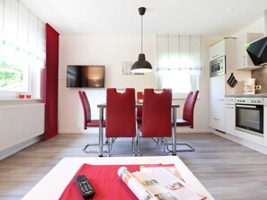 A modern kitchen with white cabinets, a built-in oven, and a coffee maker.