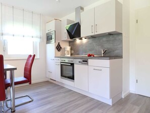 A modern kitchen with white cabinetry, a built-in oven, and a coffee maker.