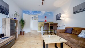 Un salon moderne avec un plancher en bois, un canapé en cuir marron, une table basse et un coin repas comprenant une table et des chaises.