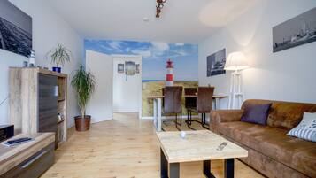 Ein modernes Wohnzimmer mit Holzboden, einem braunen Ledersofa, einem Couchtisch und einem Essbereich mit Tisch und Stühlen.