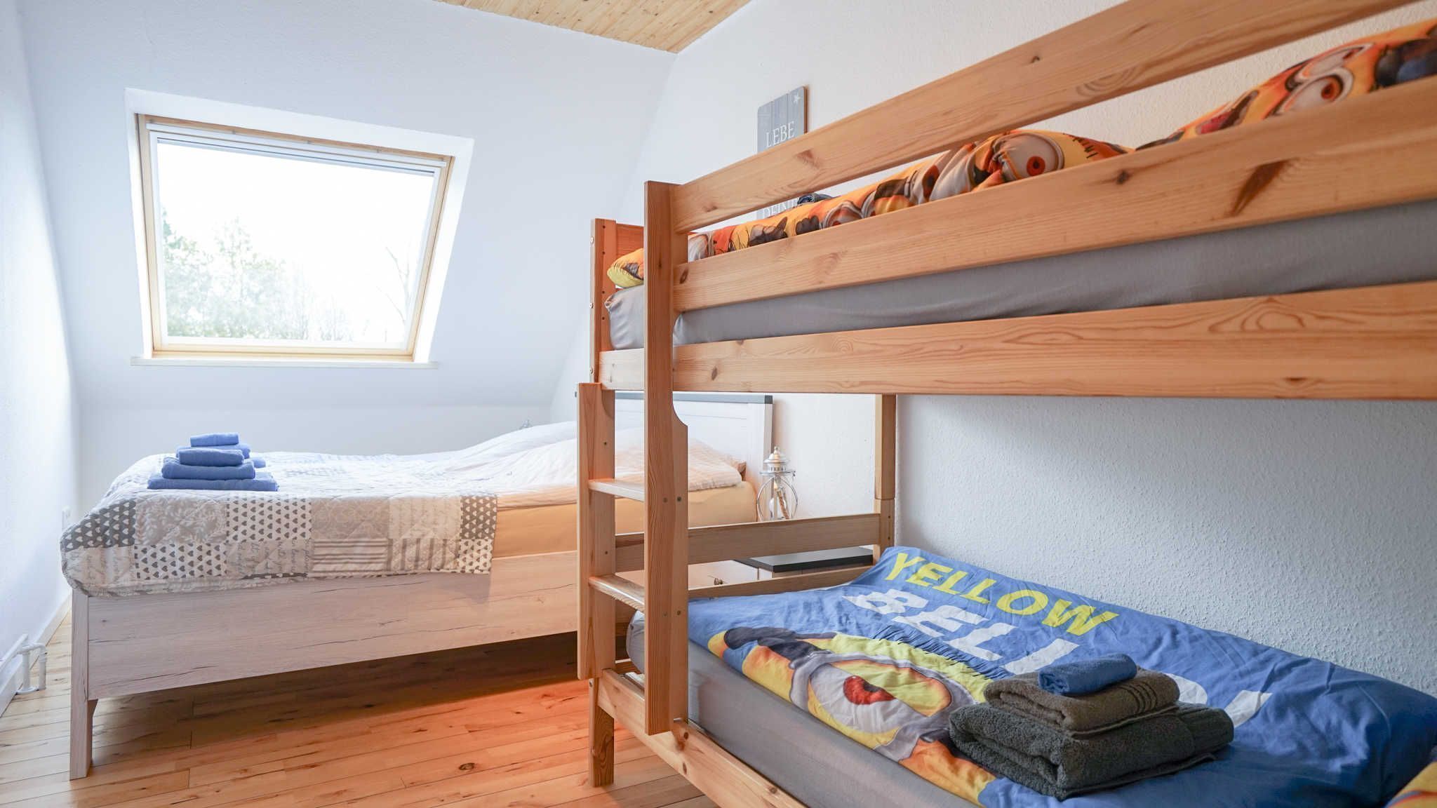 Ein Schlafsaalzimmer mit Etagenbetten, einem Fenster und einem Nachttisch mit Lampe.