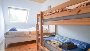 Une chambre de dortoir avec des lits superposés, une fenêtre et une table de chevet avec une lampe.