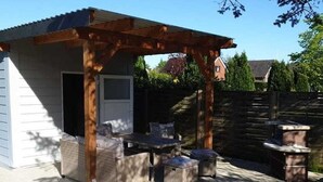 An outdoor patio with a pergola, wicker furniture, and a stone fire pit.