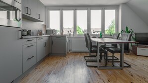 A modern kitchen with grey cabinets, a wooden floor, and a dining area with a table and chairs.
