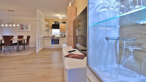 A modern kitchen with wooden cabinets, a built-in oven, and a dining area with a table and chairs. - Seebach Whg. S01, Deutschland (Ostseebad Boltenhagen)