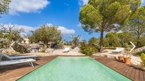 A clear pool with wooden deck, lounge chairs, and surrounding trees. - Villa Lusso (salve)