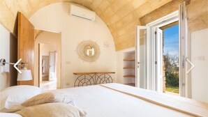 A bedroom with a bed, a circular wall decoration, and a view through an open door. - Villa Lusso (salve)
