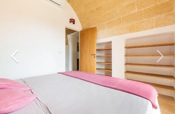 A bedroom with a bed, a wooden wardrobe, and a small door leading to another room. - Villa Lusso (salve)