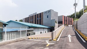 Un espace de stationnement avec un bâtiment portant l’inscription « DRYAN HOTEL » et une structure surmontée d’un toit bleu.