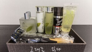 Une boîte en bois contenant des produits de toilette, notamment un rasoir, de la mousse à raser et du gel coiffant.