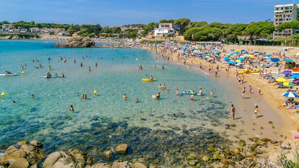 A crowded beach with clear water, umbrellas, and people enjoying the sun. - Can Xirau Castle | Private Pool Sea Views Air Conditioning Ideal Families (SANTA SUSSANA)