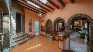 A spacious interior with a high ceiling, exposed wooden beams, and a central bar area. - Can Xirau Castle | Private Pool Sea Views Air Conditioning Ideal Families (SANTA SUSSANA)