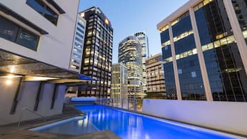 Una piscina al aire libre, sombrillas, sillones reclinables de piscina