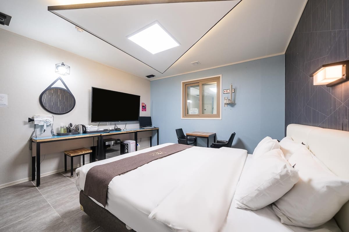 Habitación de hotel con cama, escritorio y televisor de pantalla plana.