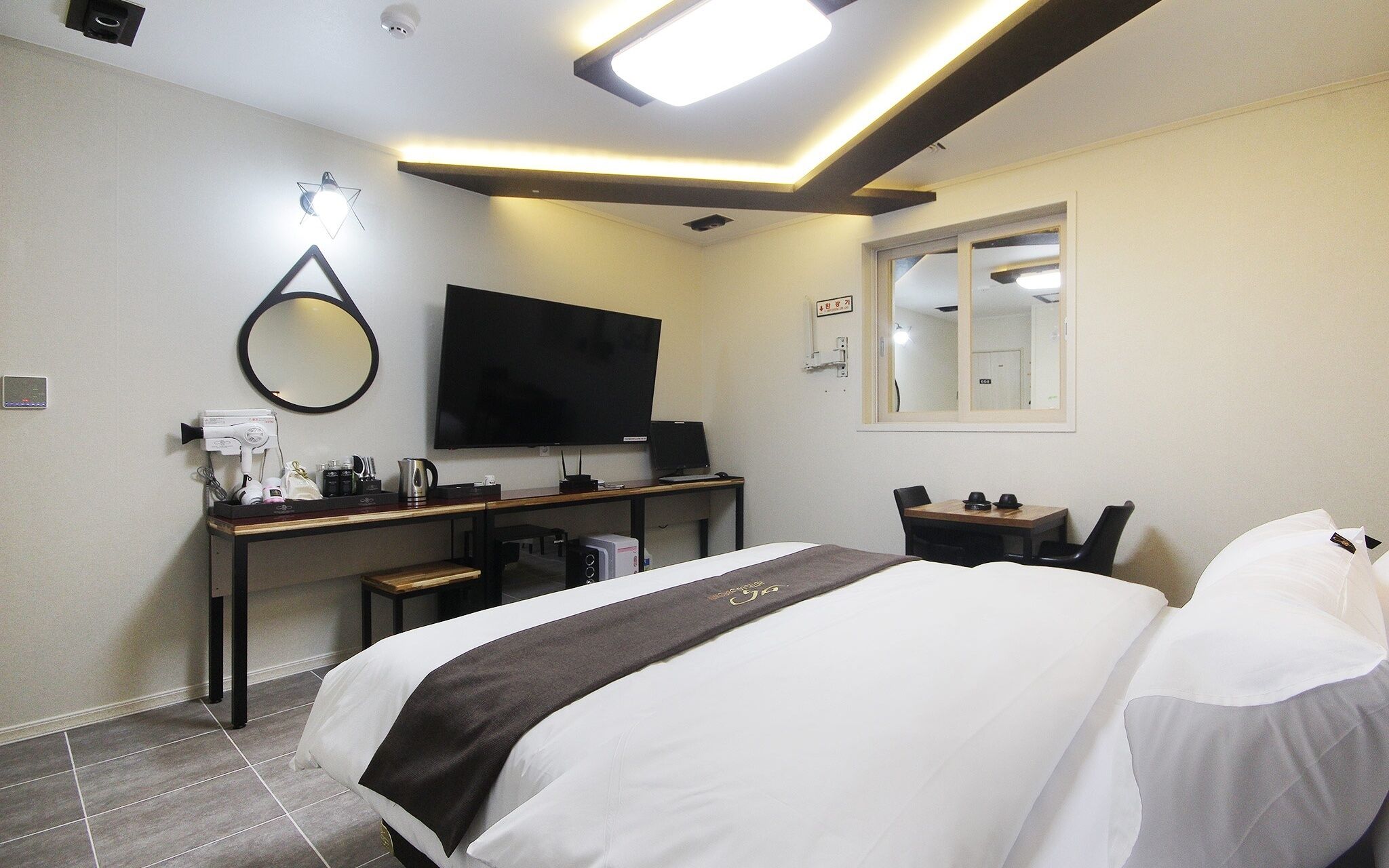A hotel room with a bed, desk, and TV.